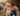 Photo of a woman in a tank top, jeans, and hiking boots kissing her golden retriever dog
