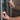 Close-up of a hand holding a needle-free bottle adaptor for VetIMMUNE PI while reaching for a refrigerator.